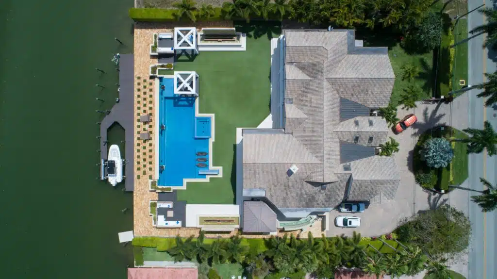 modern coastal home with pool, lush landscaping, and scenic waterway views.